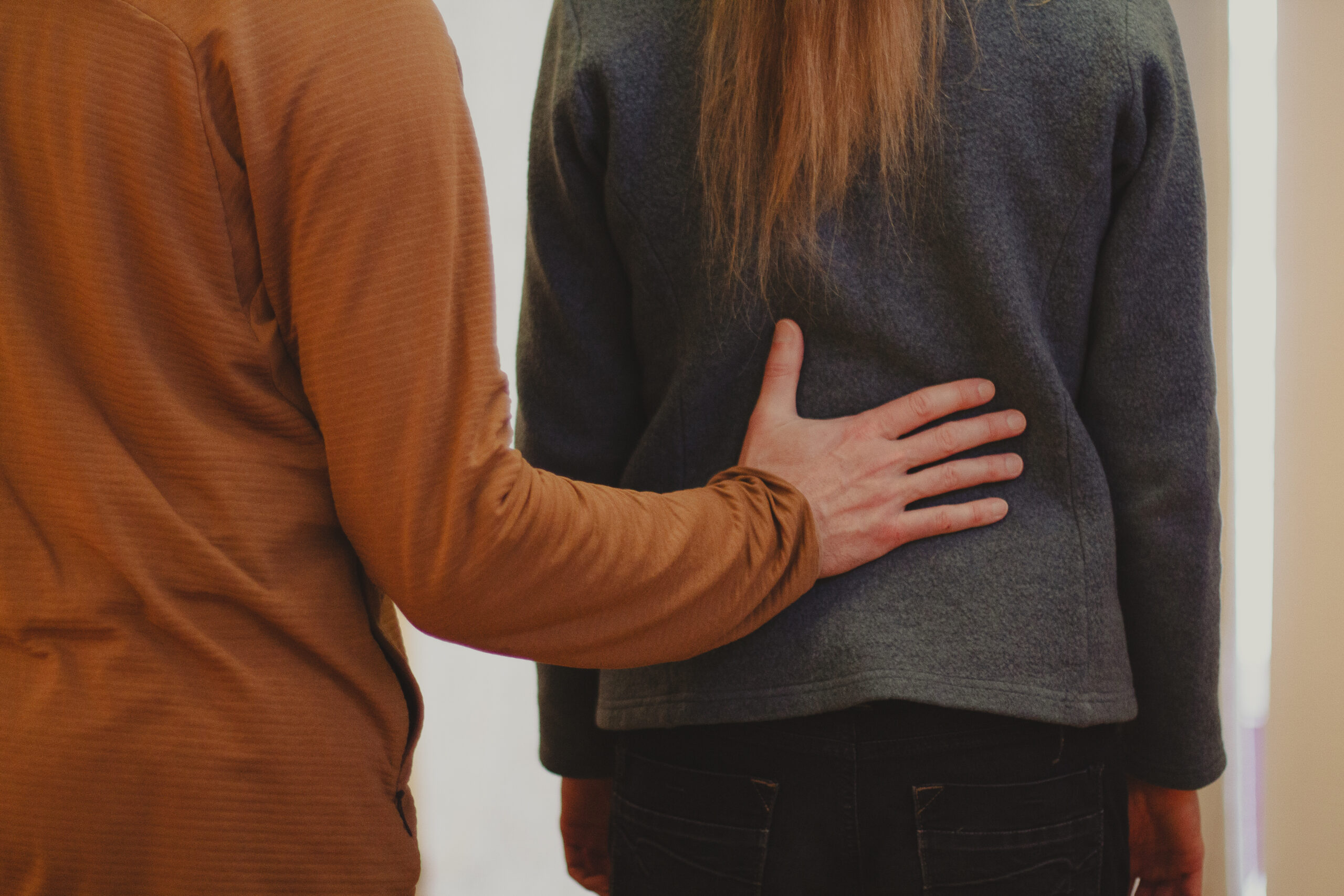 Ein Alexandertechnik-Lehrer legt seine Hand auf den Rücken einer Klientin.
